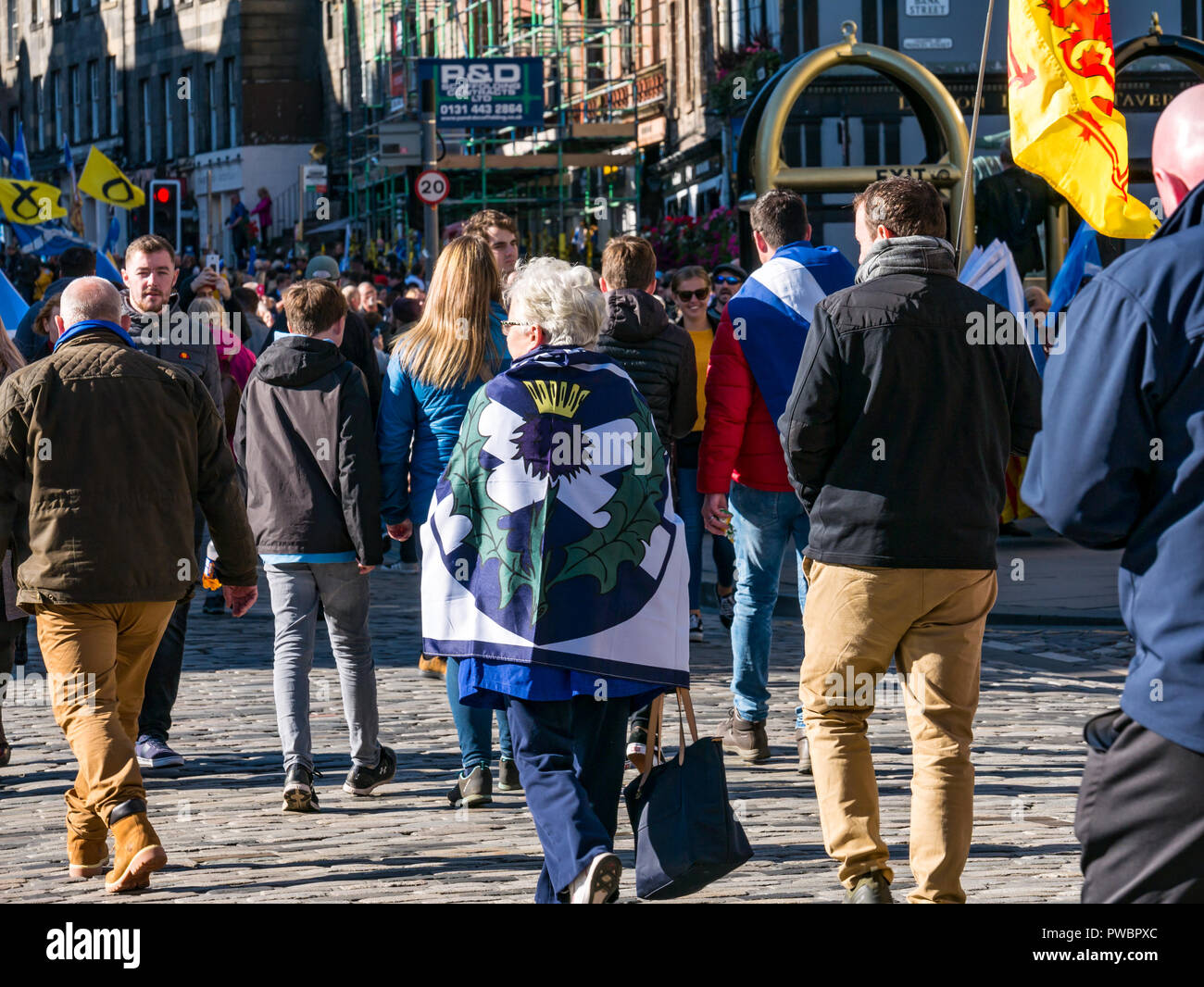 Persone vestite con bandiere nazionali che unisce tutti sotto uno striscione indipendenza scozzese marzo 2018, Royal Mile di Edimburgo, Scozia, Regno Unito Foto Stock