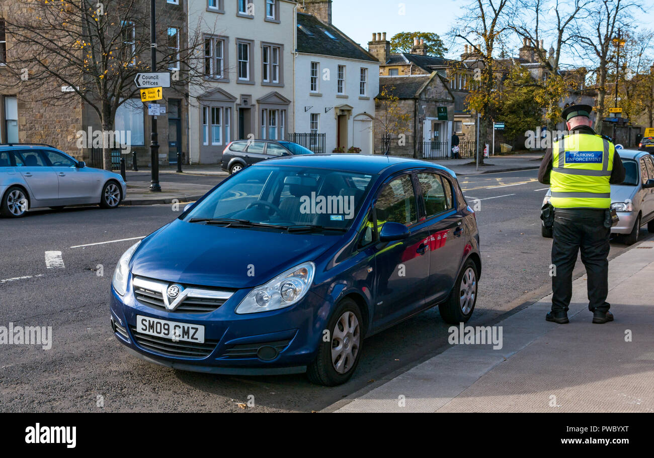 Traffic Warden addetto all'applicazione del parcheggio che scrive i dettagli delle informazioni sulle auto, Court Street, Haddington, East Lothian, Scozia, Regno Unito Foto Stock