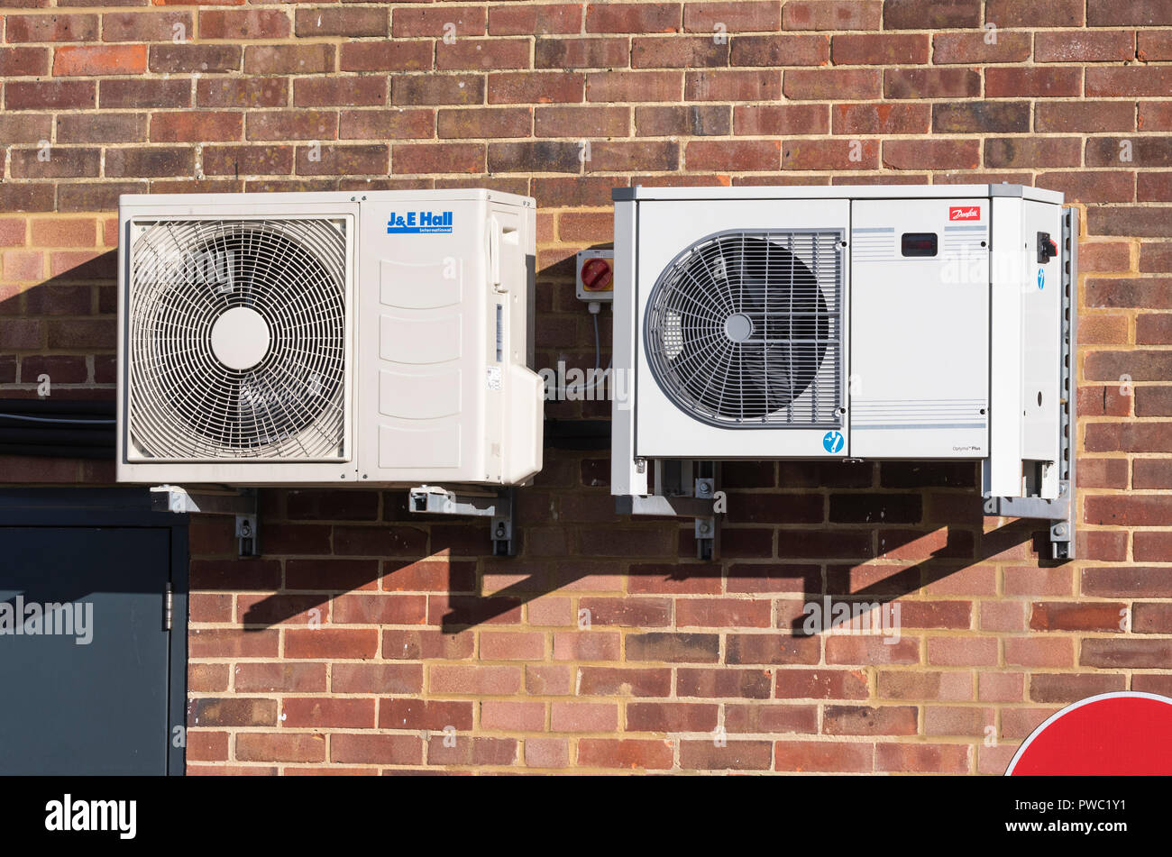 Coppia di commerciali di piccole dimensioni di condensazione ad aria unità di refrigerazione per shop aria condizionata montato su una parete esterna del Regno Unito. Foto Stock