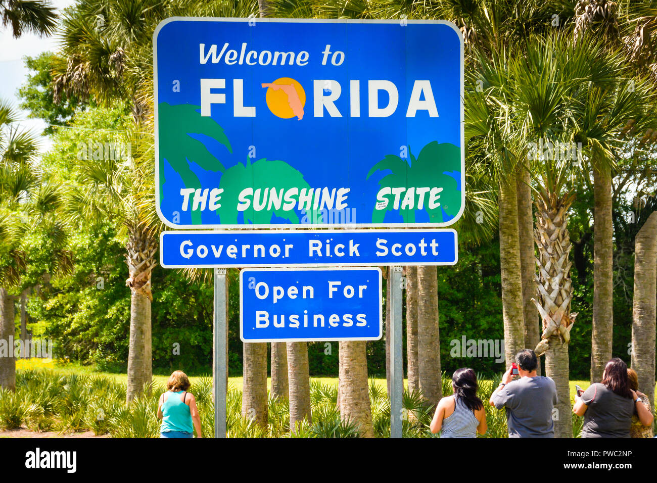 Tirare i turisti oltre a prendere foto con blu brillante di 'Benvenuto Florida' lo stato del sole segno al confine di stato con palme in linea della Florida Foto Stock