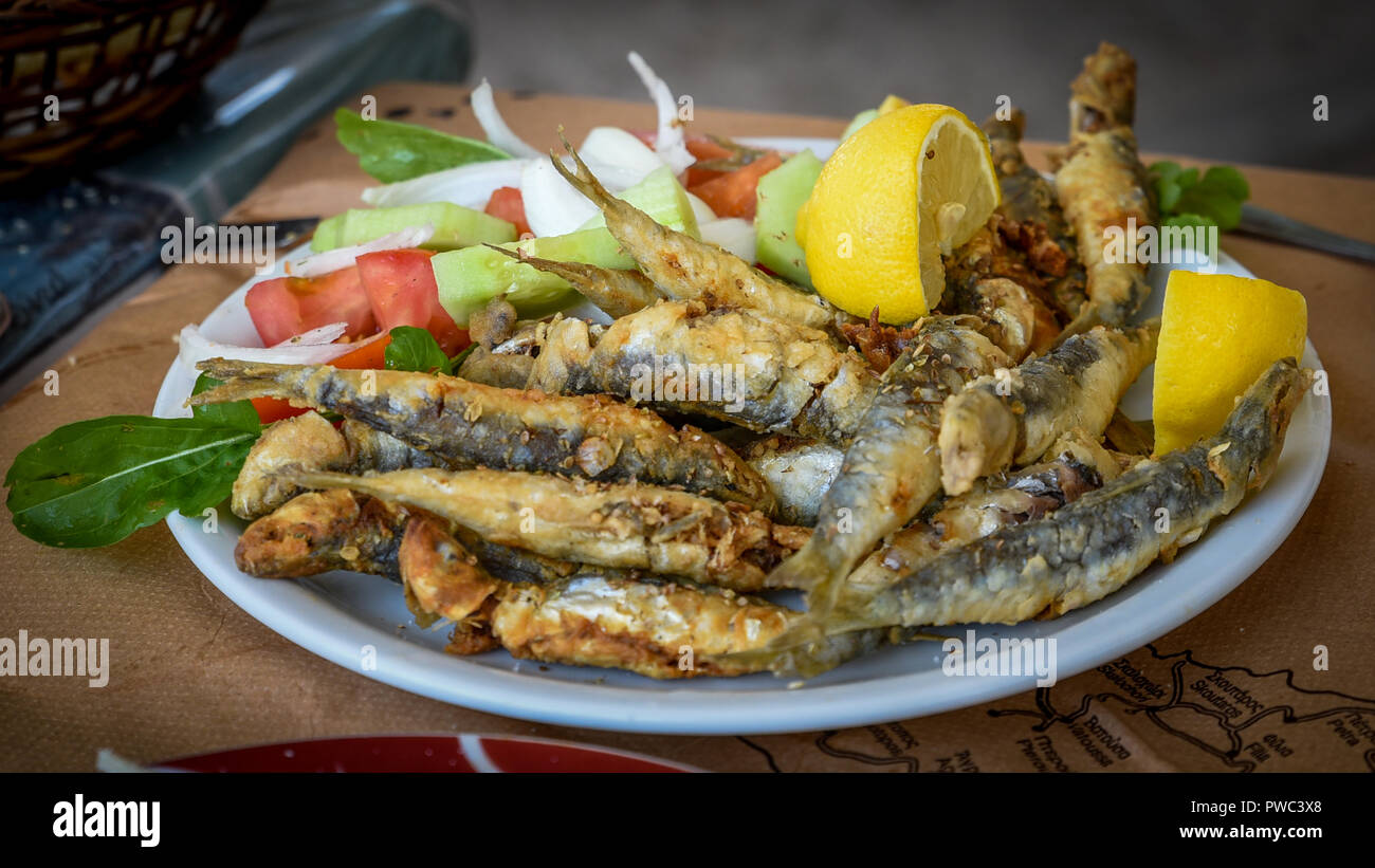 Fried puzzava di pesce su una piastra con insalata Foto Stock