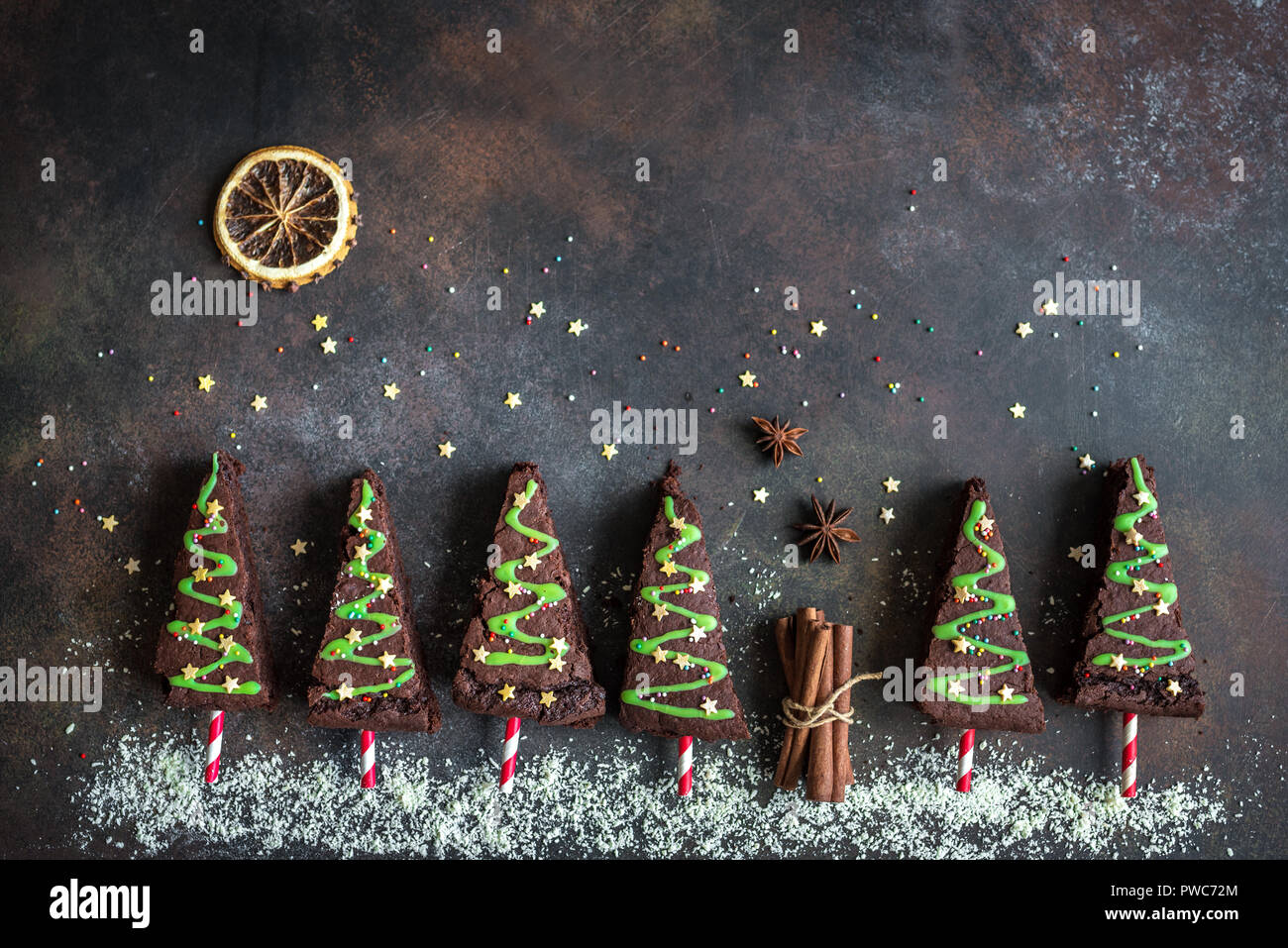 Brownie al cioccolato a forma di alberi di Natale con la glassa verde e festosa spruzzino, vista dall'alto, copia dello spazio. Dolce Natale o vacanze invernali pasticceria Foto Stock