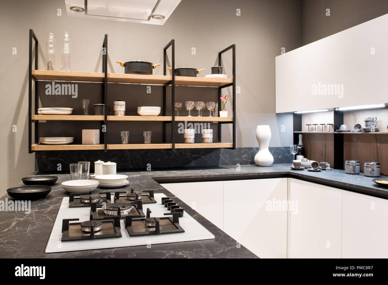 Compact montato interno cucina con fornelli a gas in un effetto marmo contatore e scaffali con stoviglie Foto Stock