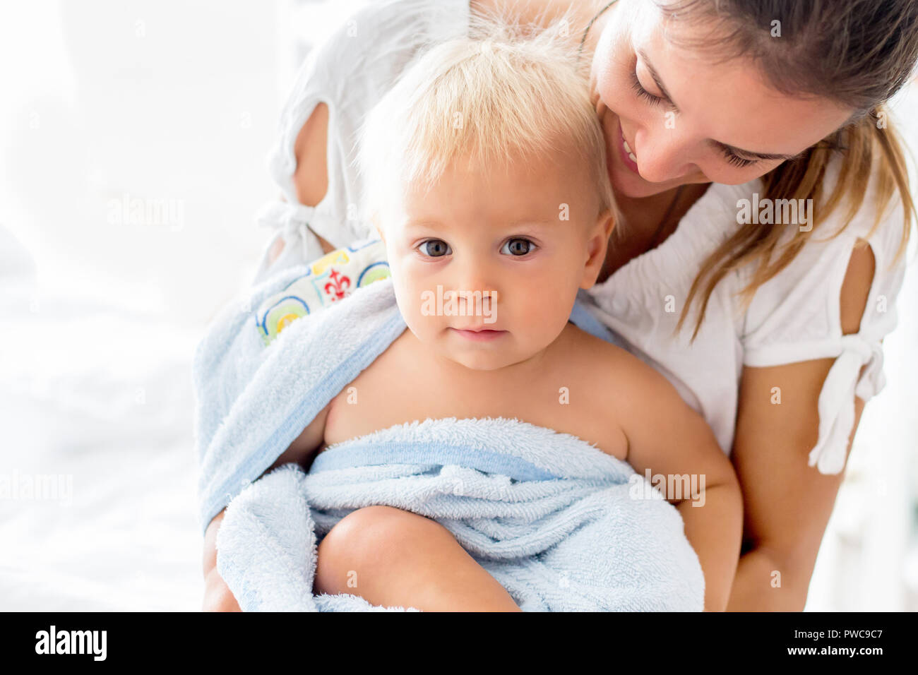 Giovane mamma, giocando con il suo bimbo baby boy dopo il bagno nella soleggiata camera da letto Foto Stock