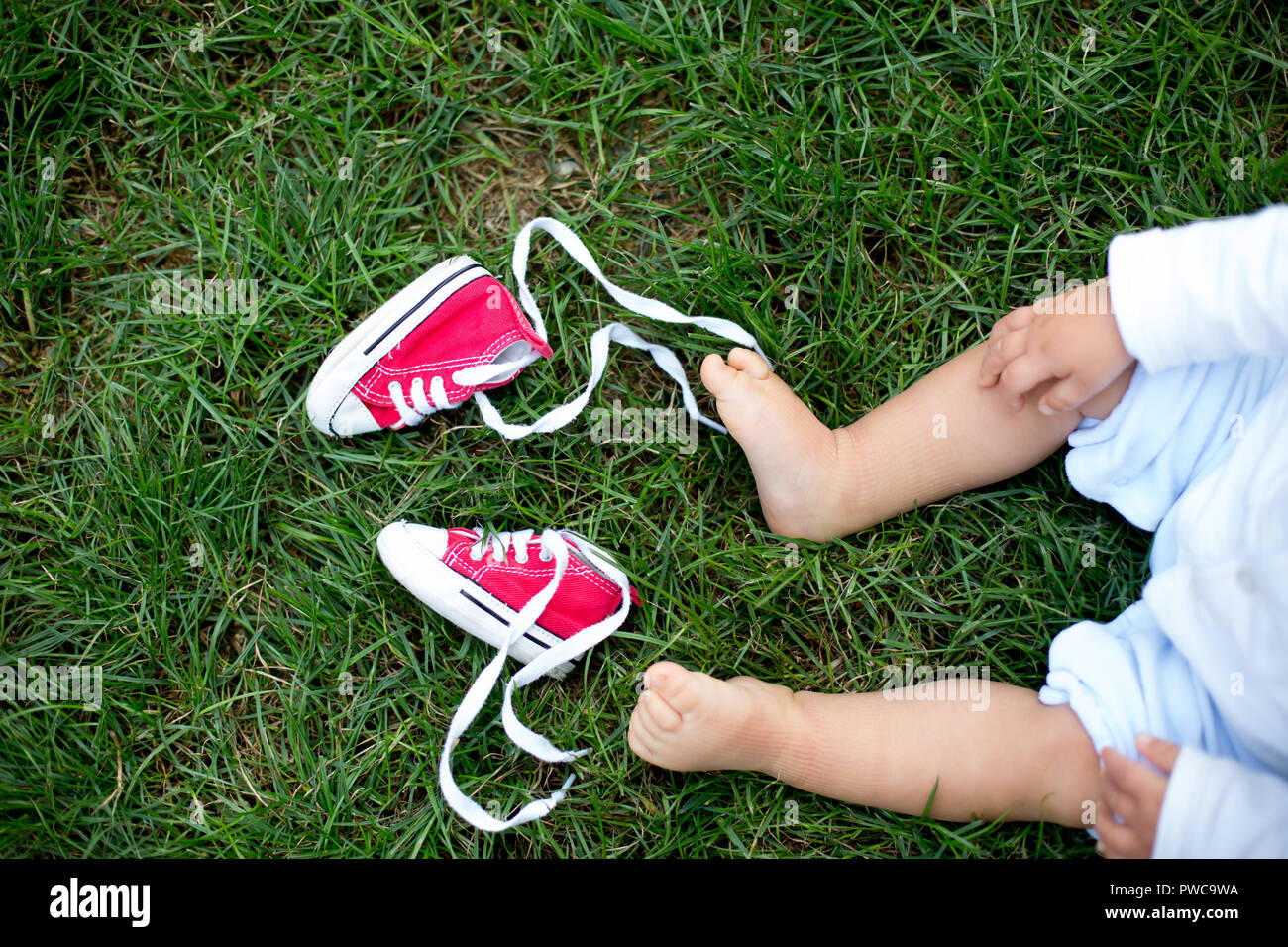 Red baby toddlers sneakers e white woman sneakers sull'erba con po' di piedi del bambino Foto Stock
