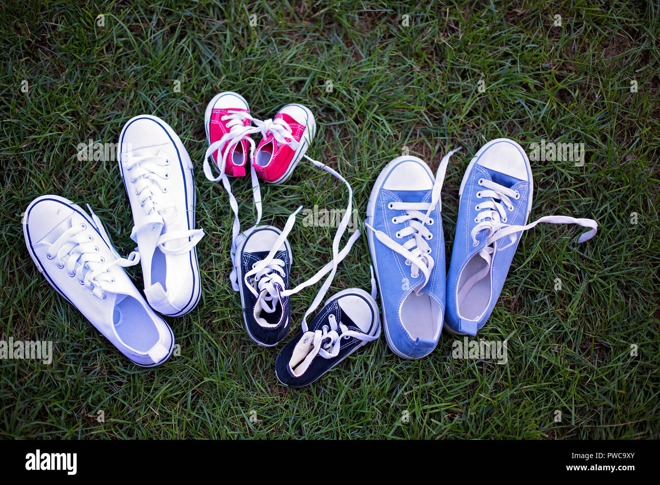 Quattro diversi colori coppia di sneakers, scarpe per tutta la famiglia  sdraiati sull'erba Foto stock - Alamy