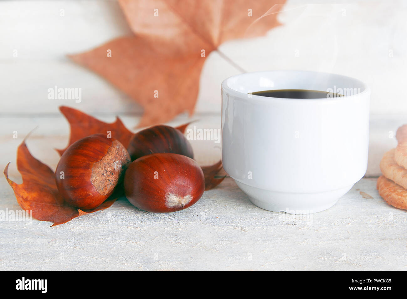 Bevanda calda, una tazza di caffè in un tradizionale catalano Halloween party castanyada. Tre le castagne su un foglio bianco e un tavolo di legno. Svuotare lo spazio di copia per e Foto Stock