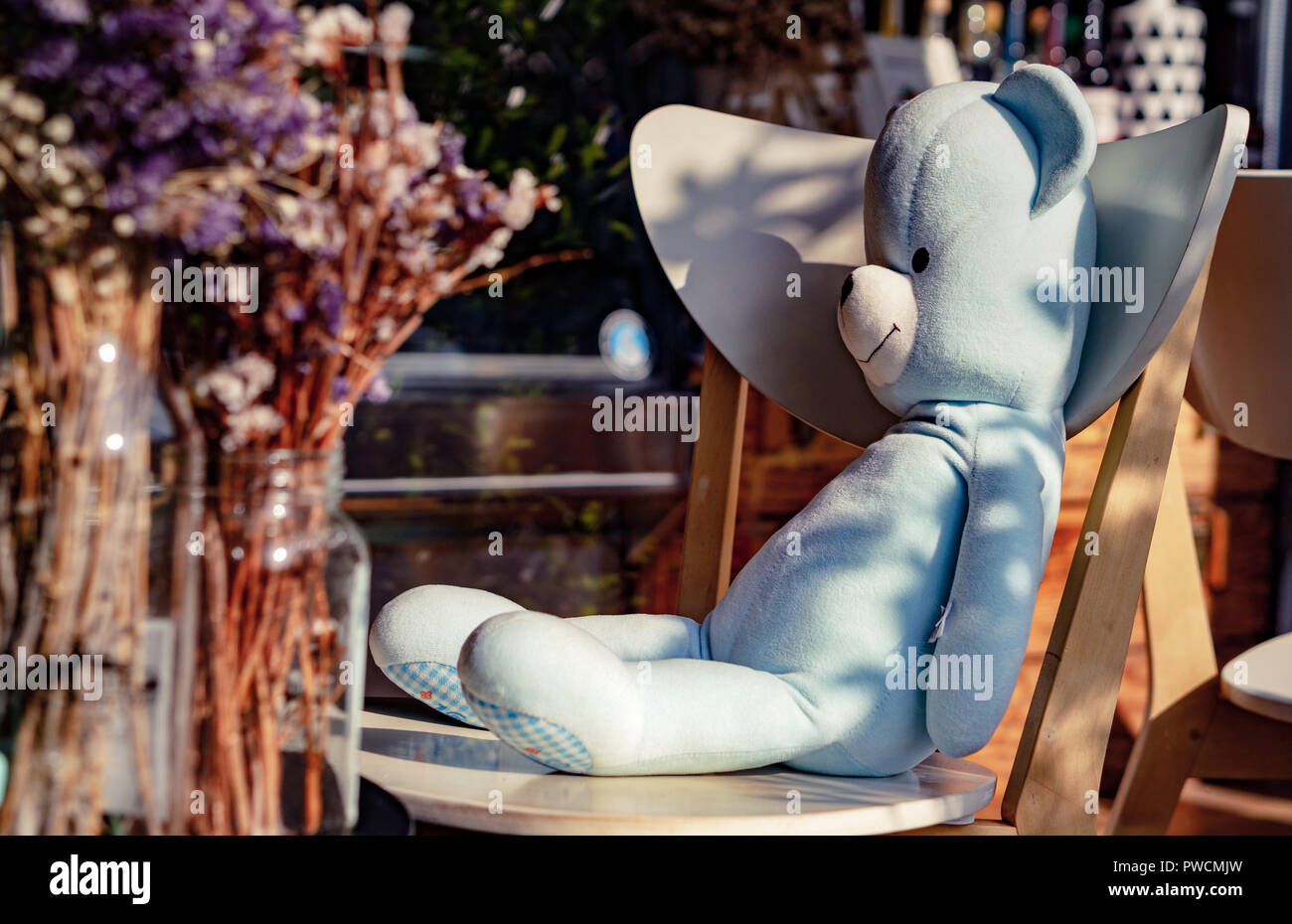 Blu grazioso orsacchiotto giocattolo seduto sulla sedia nel panificio coffee shop.Concetto circa il momento di relax con la felicità. Decorazione Home idea creativa . Foto Stock
