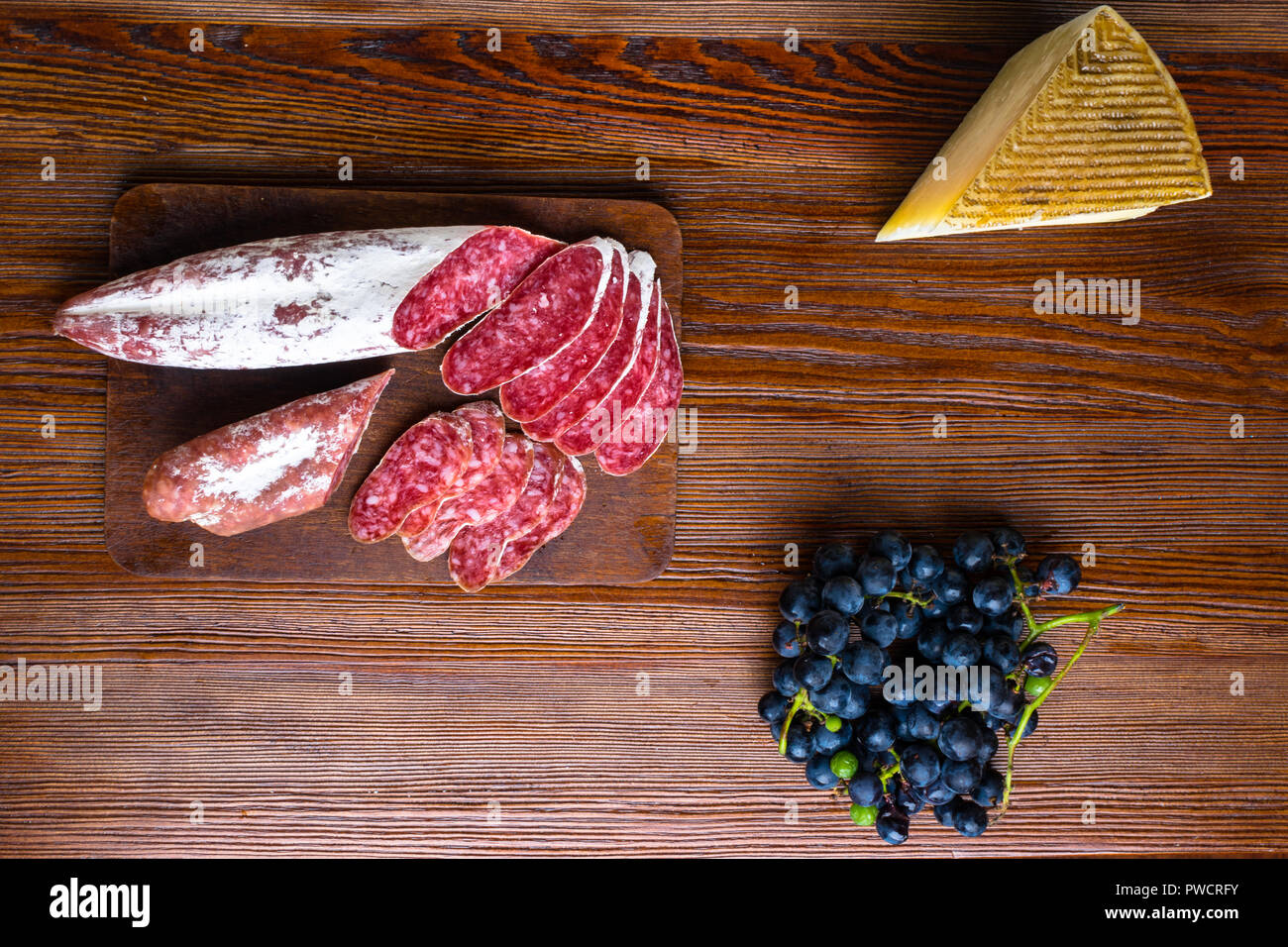 Spuntini e stuzzichini. Tapas spagnole sul piatto di legno. Il tapas bar. il salame chorizo, formaggio,uva. Vista superiore Foto Stock