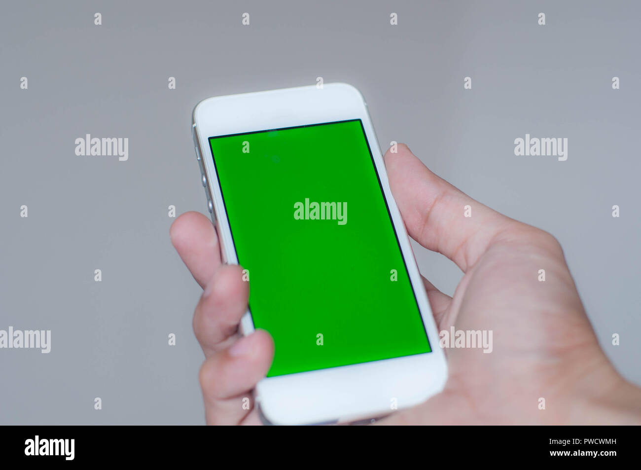 Giovane uomo in possesso di una smart phone con schermo verde Foto Stock