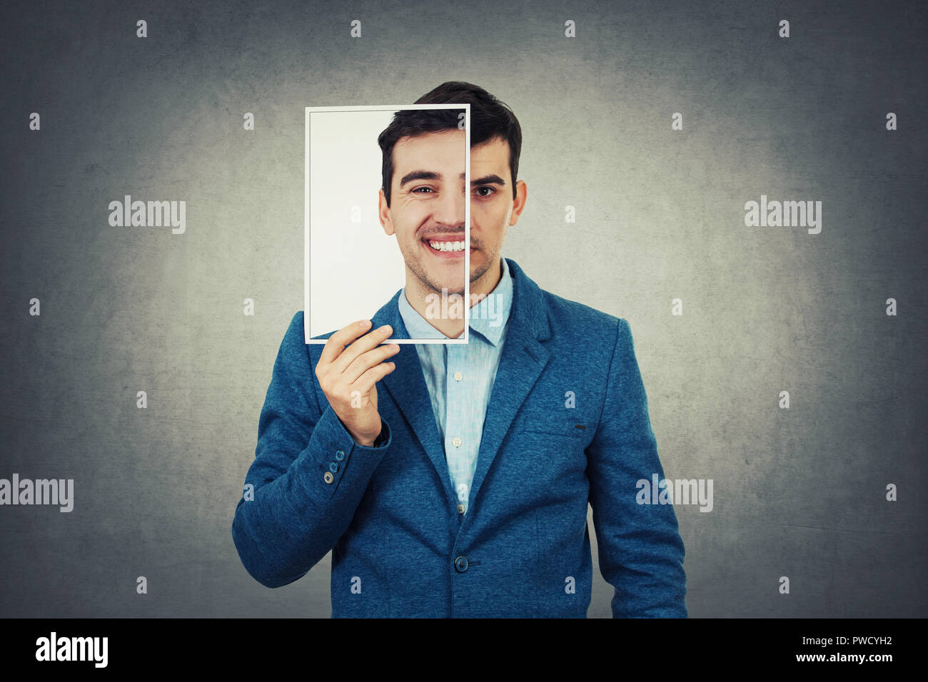 Ritratto di un imprenditore triste metà nasconde la sua faccia usando un foglio di foto ritratto con una finta felice commozione. Maschera per nascondere il vero volto di espressione, c Foto Stock