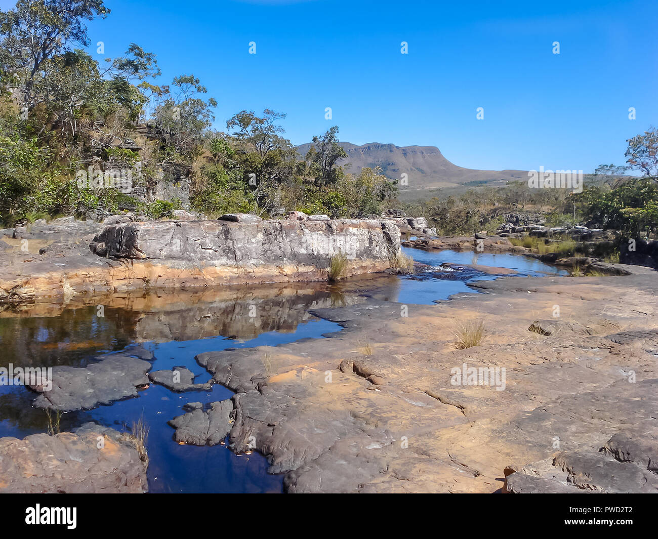Una rilassante vista a livello oculare di un ruscello che corre attraverso le rocce in primo piano e le montagne lontano in background Foto Stock