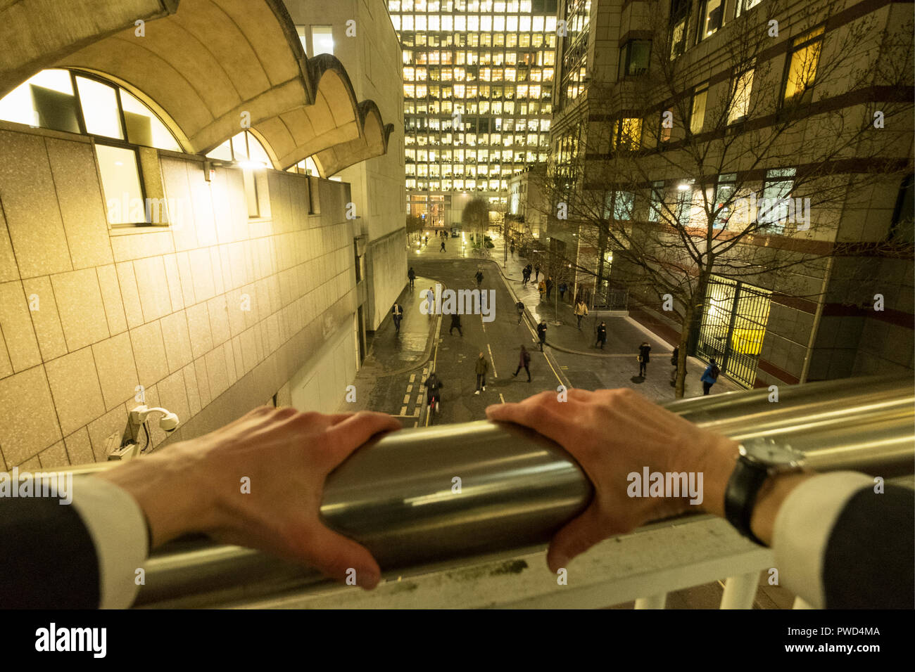 Punto di vista personale lasso di tempo di un imprenditore caucasico appoggiandosi con le mani sulle ringhiere di notte Foto Stock