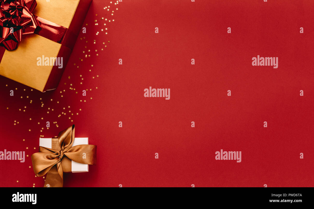 Varie confezioni regalo con piccole stelle dorate su sfondo rosso. Vista dall'alto i regali di Natale con le stelle. Piano di composizione dei laici con un sacco di spazio copia. Foto Stock