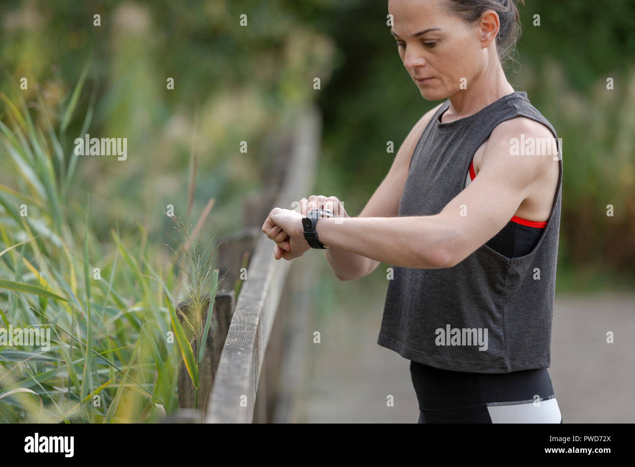 Sportivo da donna controllando il suo tracker fitness "montare bit' sul suo polso Foto Stock