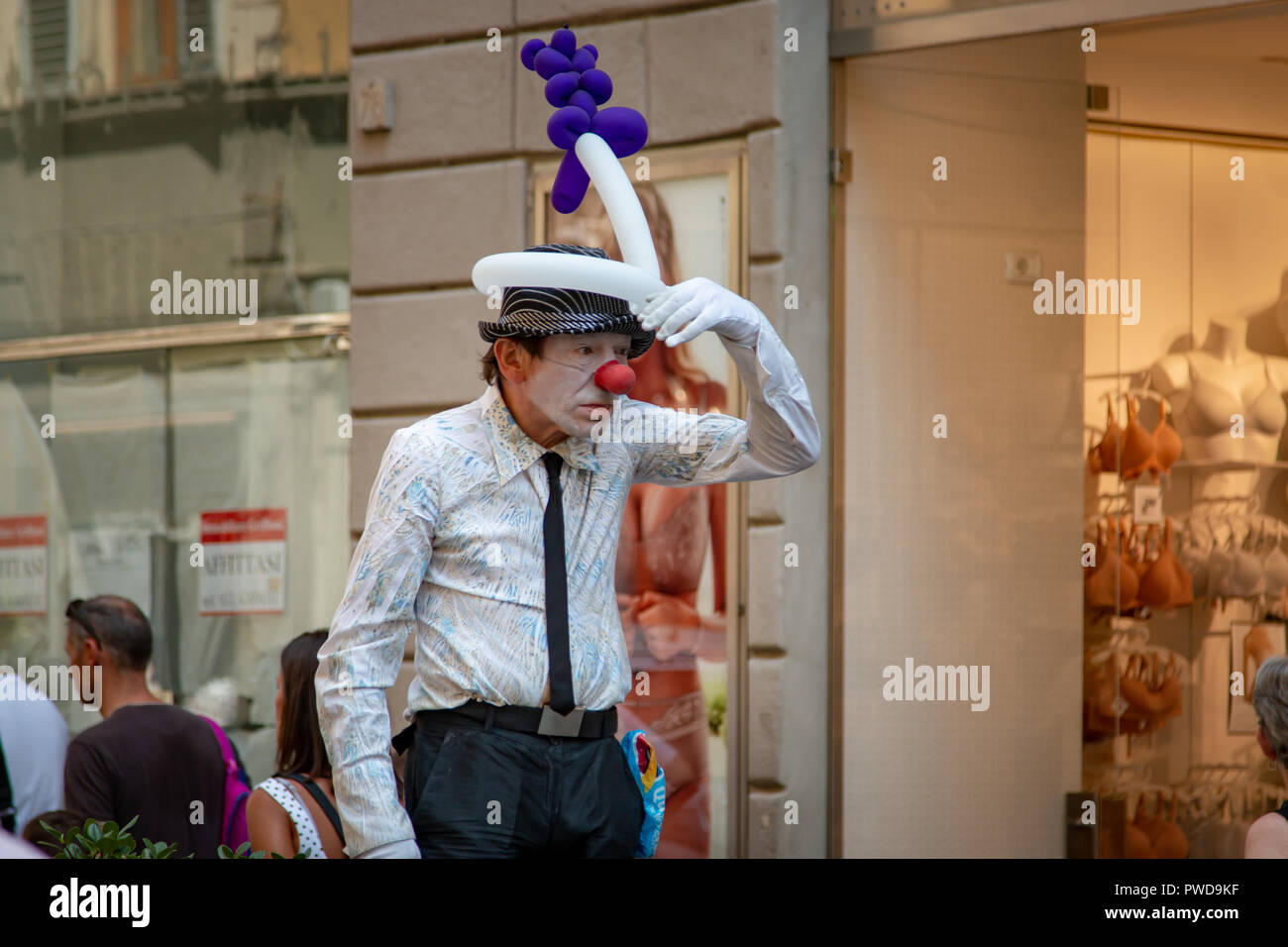 Un esecutore di strada vestito come un clown mimi cercando qualcosa o qualcuno a Firenze, Italia. Foto Stock