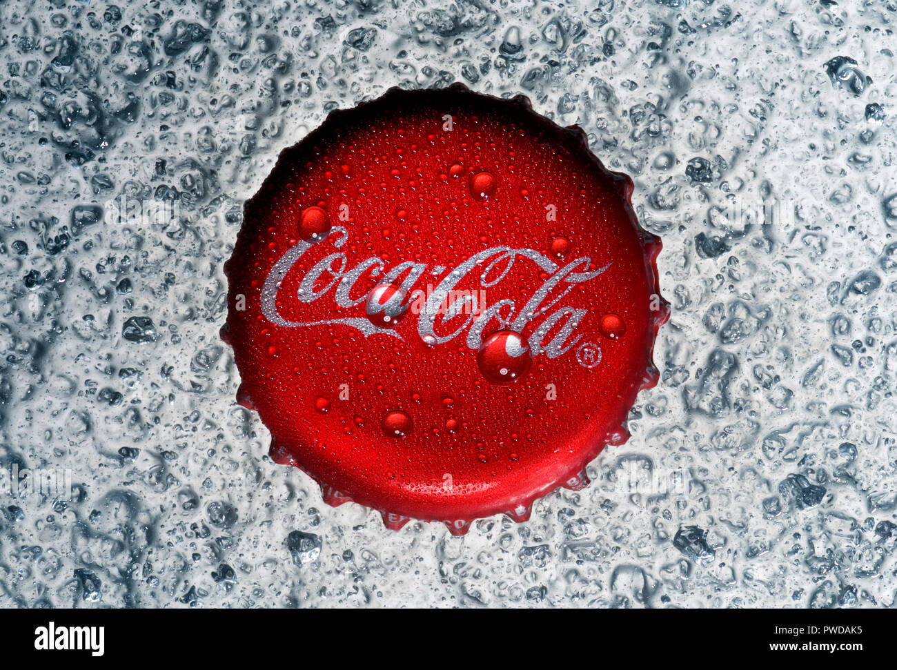 Coca Cola il cappuccio con acqua goccioli scende su uno sfondo di scaglie di ghiaccio, fresche, fresca e rinfrescante Foto Stock