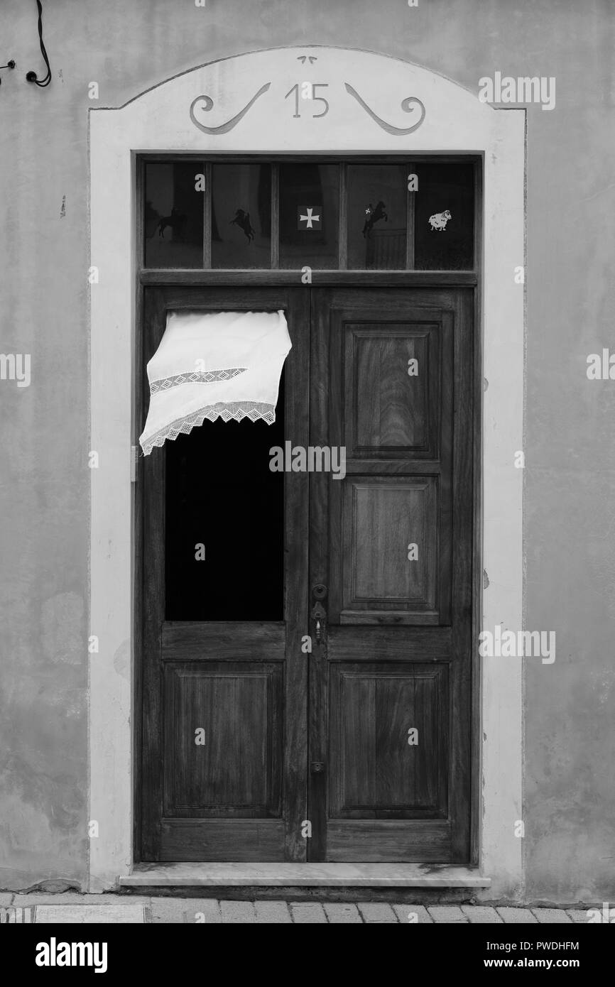 La tendina di pizzo che fluttua nel vento attraverso la finestra di una porta di legno in Ciutadella menorca Spagna Foto Stock