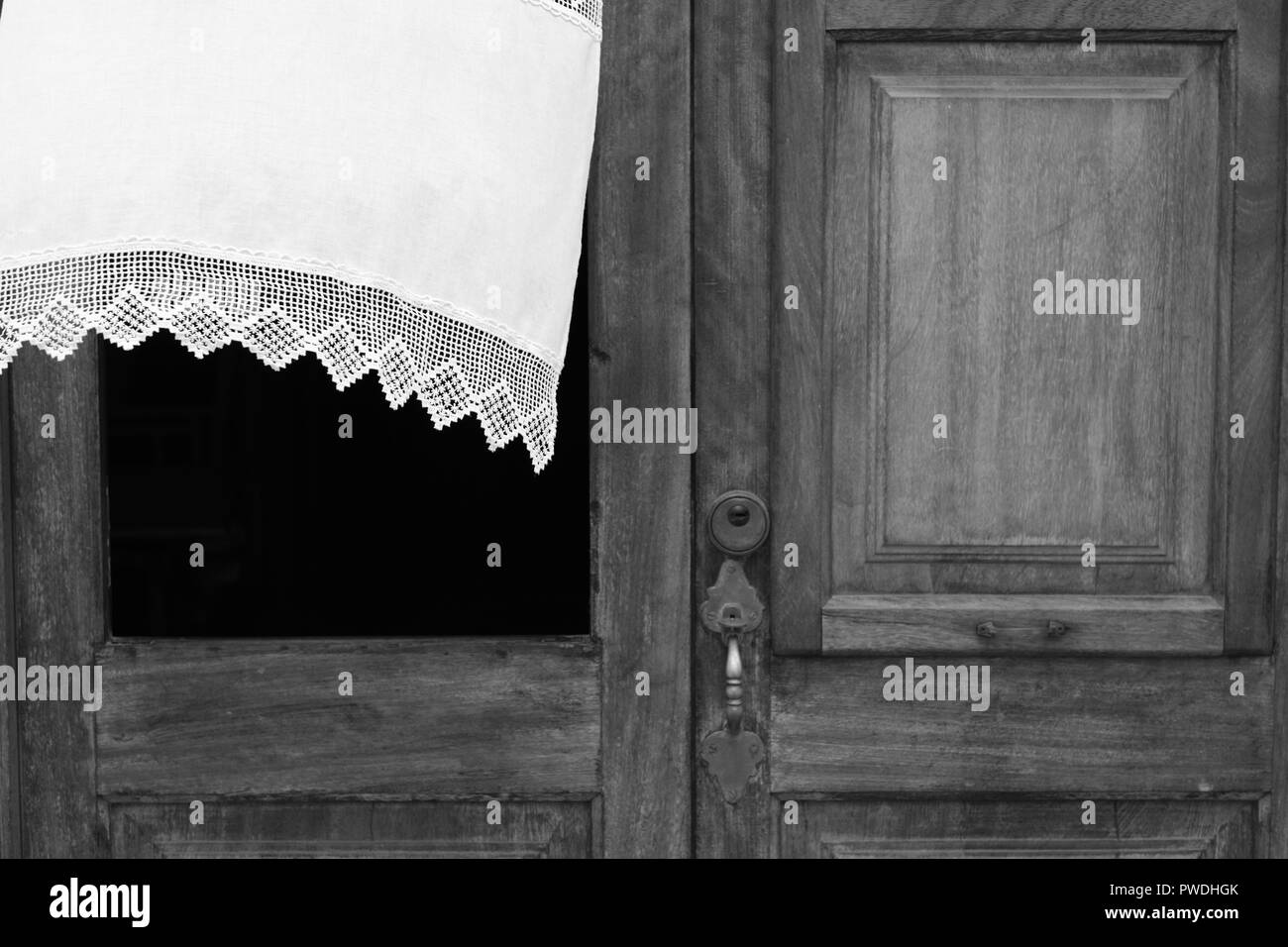 La tendina di pizzo che fluttua nel vento attraverso la finestra di una porta di legno in Ciutadella menorca Spagna Foto Stock