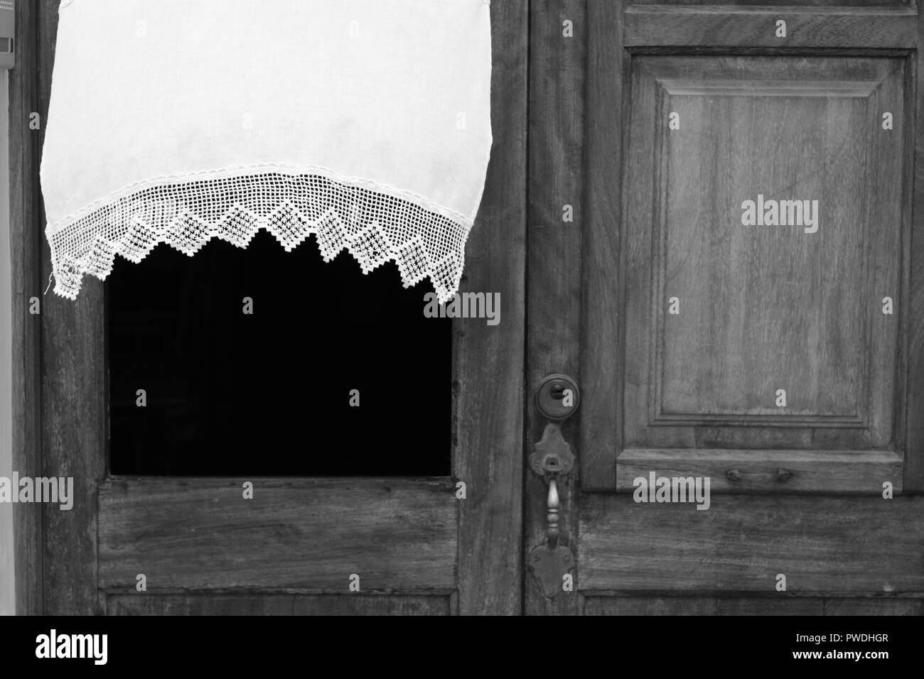 La tendina di pizzo che fluttua nel vento attraverso la finestra di una porta di legno in Ciutadella menorca Spagna Foto Stock