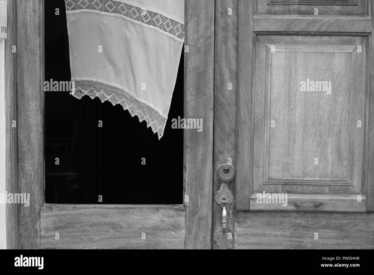 La tendina di pizzo che fluttua nel vento attraverso la finestra di una porta di legno in Ciutadella menorca Spagna Foto Stock