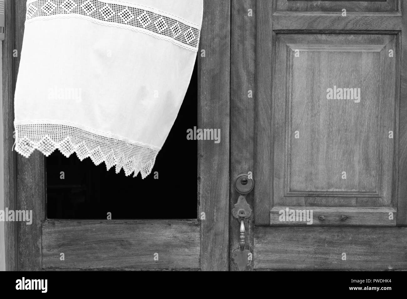 La tendina di pizzo che fluttua nel vento attraverso la finestra di una porta di legno in Ciutadella menorca Spagna Foto Stock