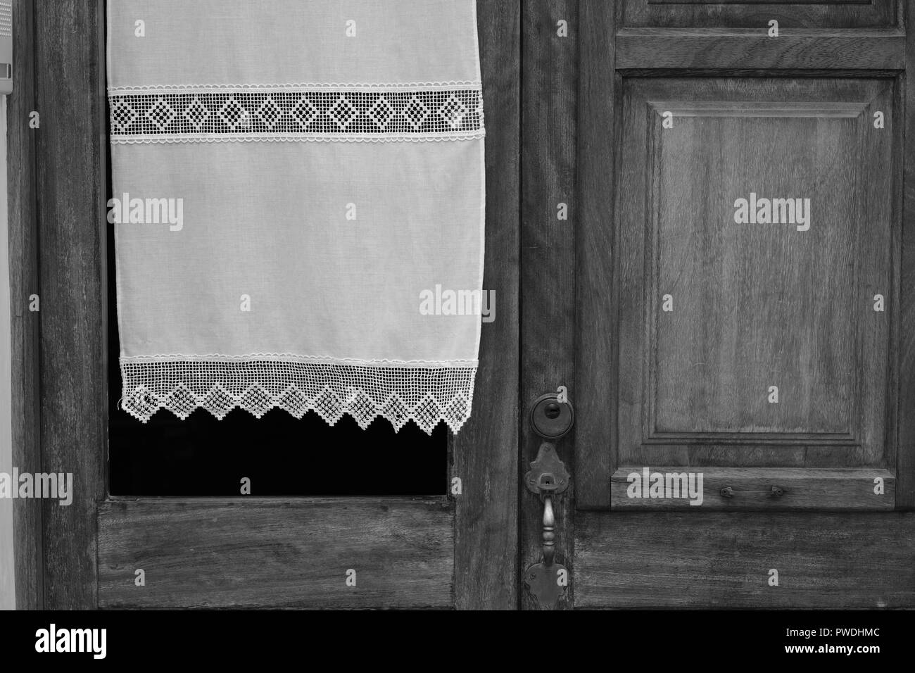 La tendina di pizzo che fluttua nel vento attraverso una finestra in una porta tradizionale in Ciutadella menorca Spagna Foto Stock