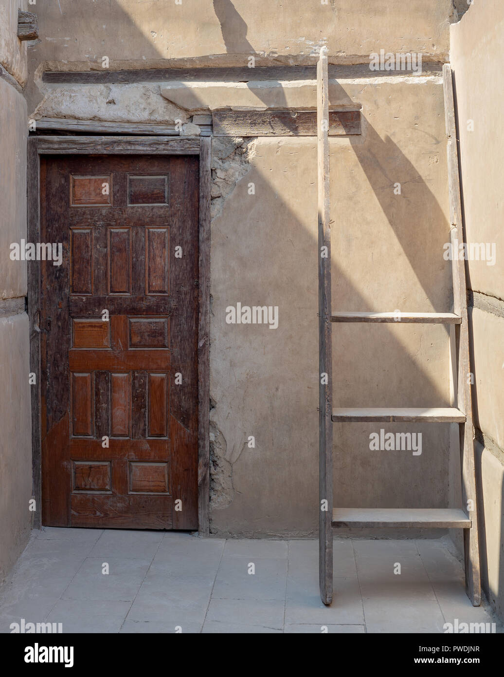 Muro di pietra con legno vecchio grunge porta decorata e rotto la scaletta in legno, il Cairo, Egitto Foto Stock