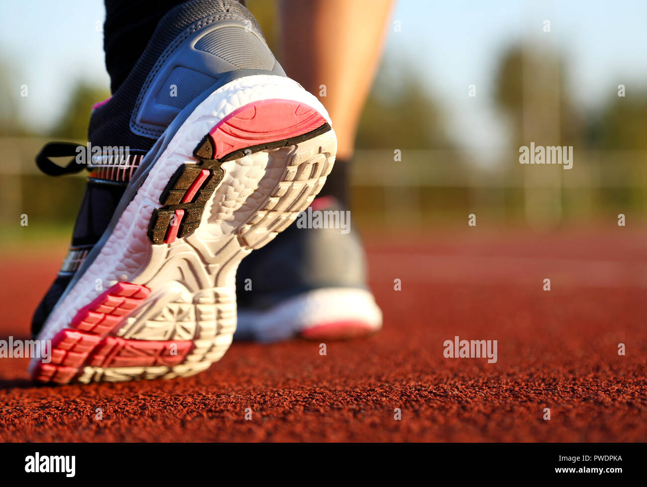 Donna in corsa su pista di atletica leggera a pomeriggio Foto Stock