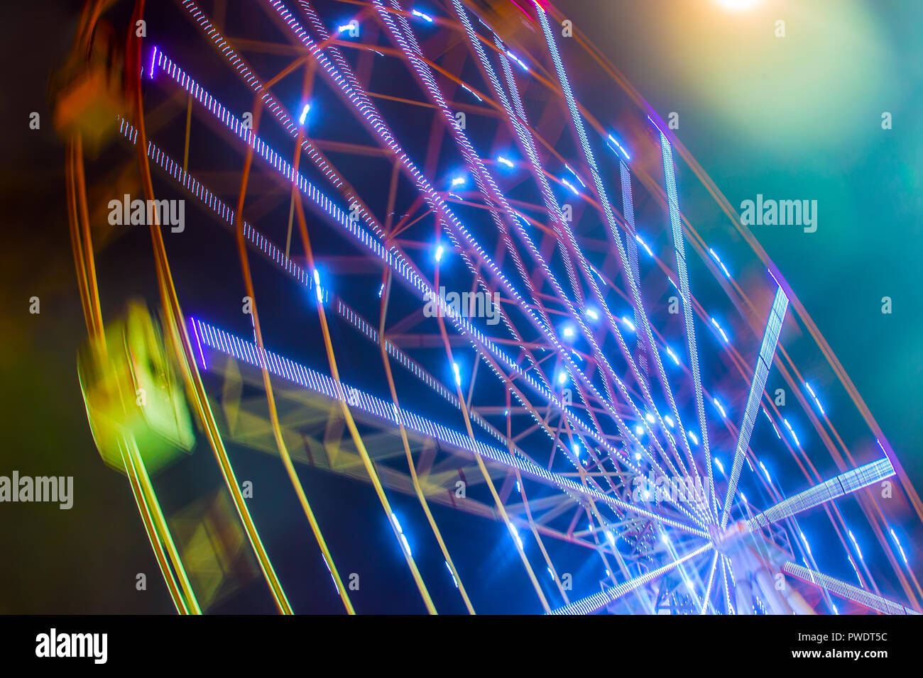 Carnival ride che mostra una filatura ruota panoramica Ferris in azione- lunga esposizione shot. Foto Stock