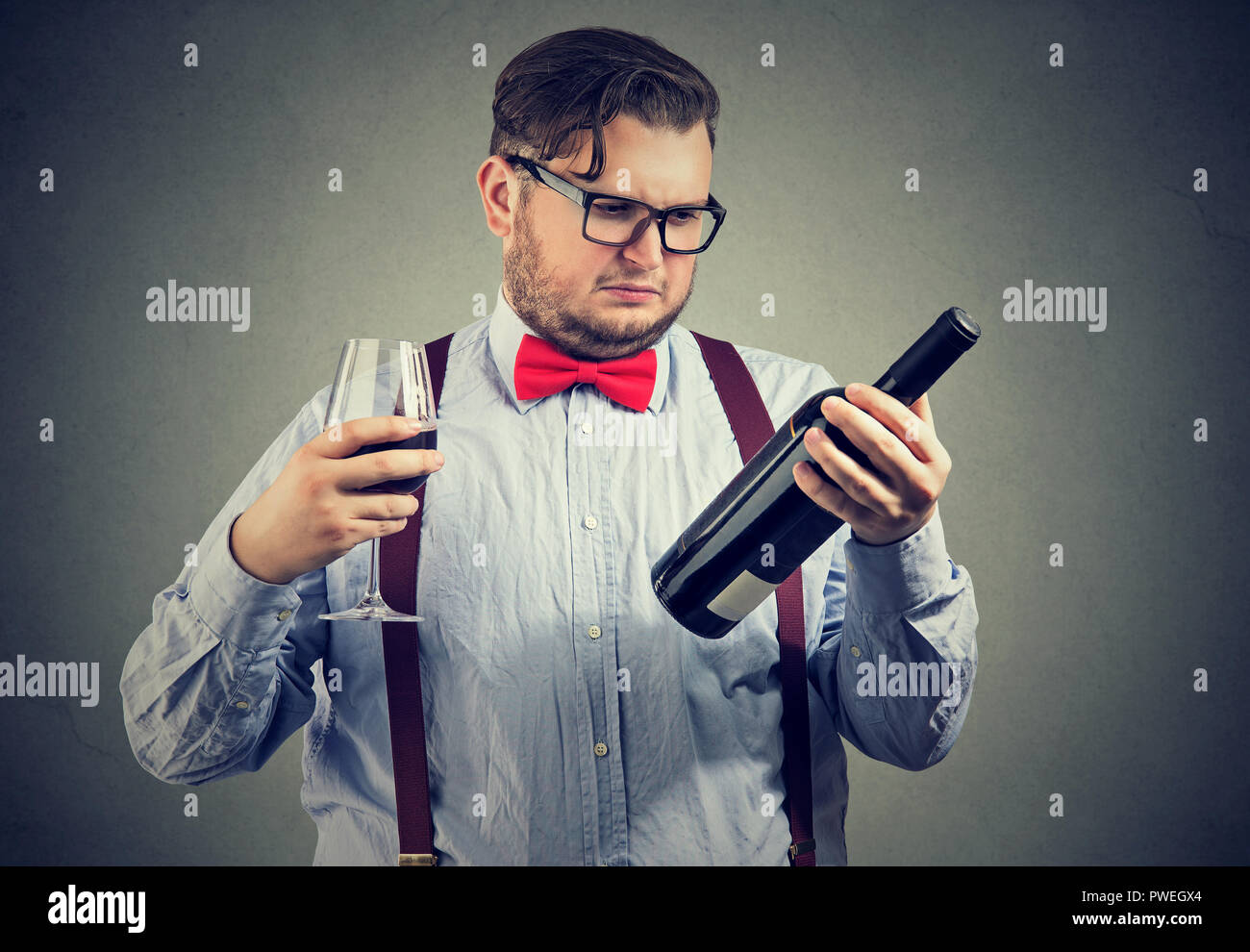 Orinato infastiditi uomo guardando una bottiglia di vino rosso Foto Stock