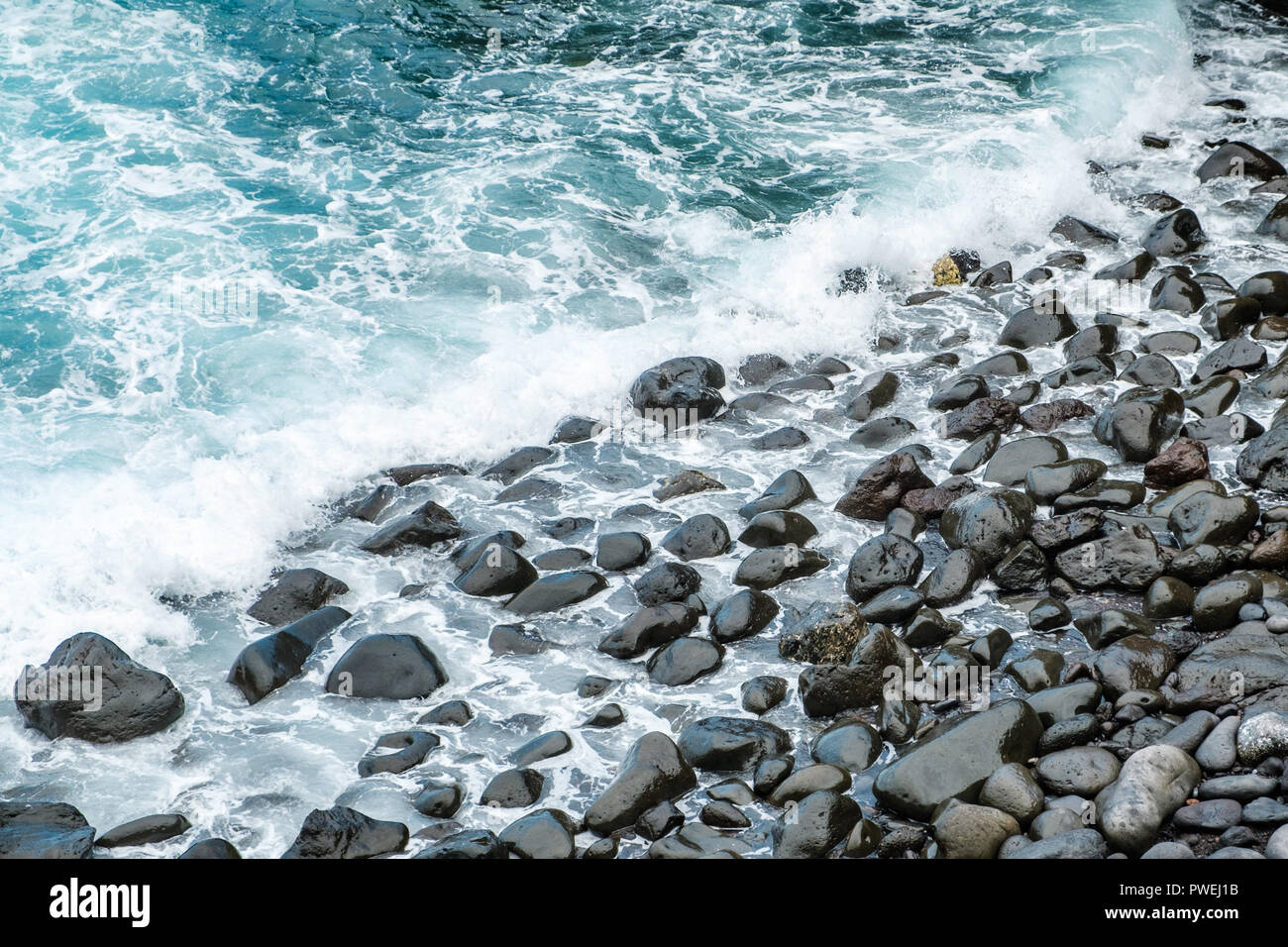 Le onde del mare su nero ciottoli costa - Foto Stock