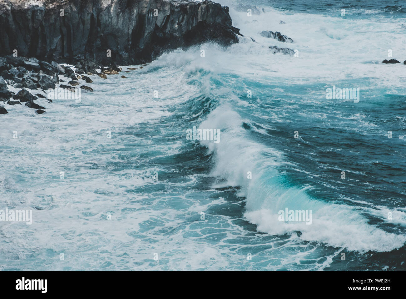 Forme d'onda colpendo coastling - nero scogliera sulla costa dell'oceano Foto Stock