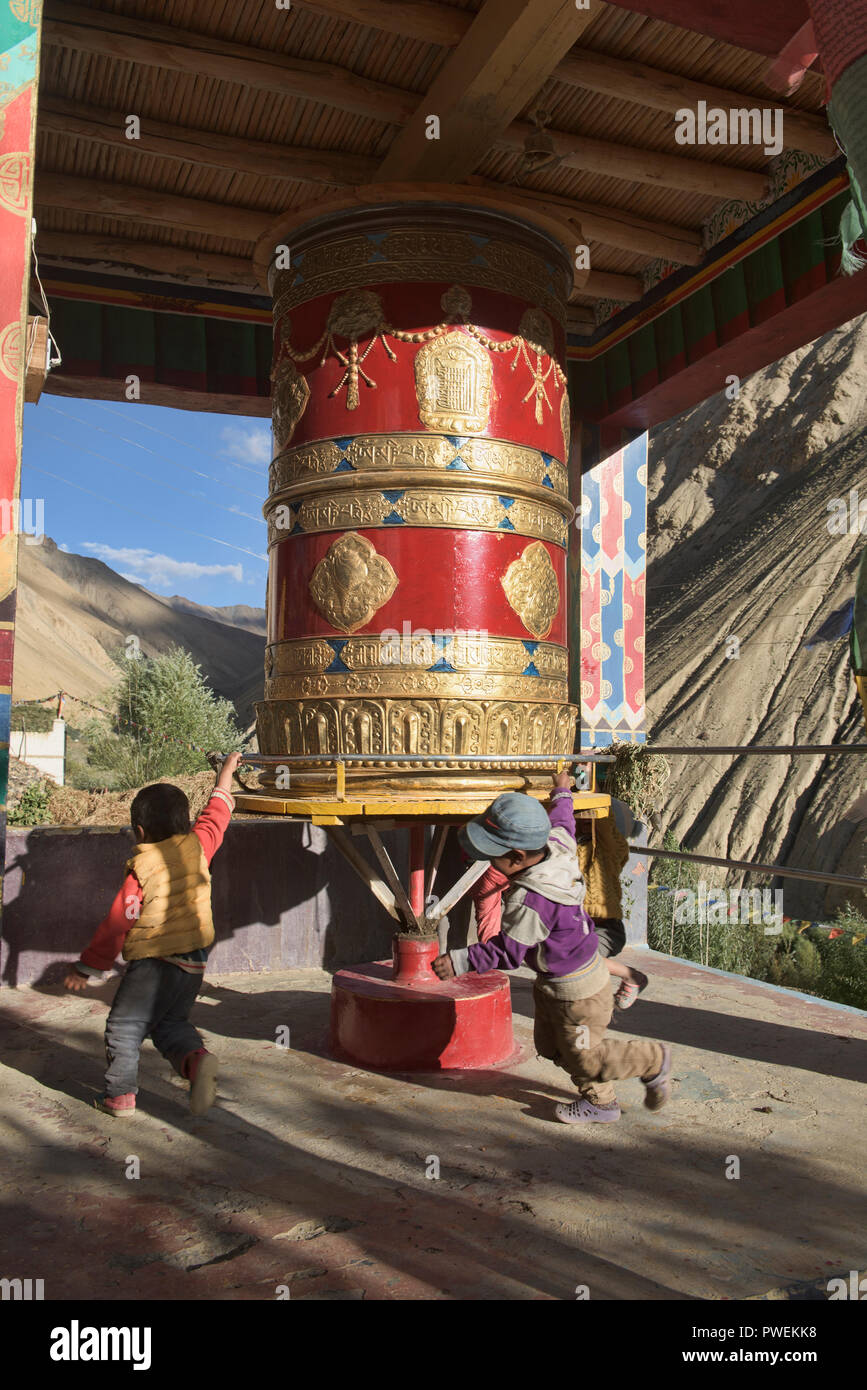 I ragazzi si gioca su una gigantesca ruota di preghiera, Hinju, Ladakh, India Foto Stock