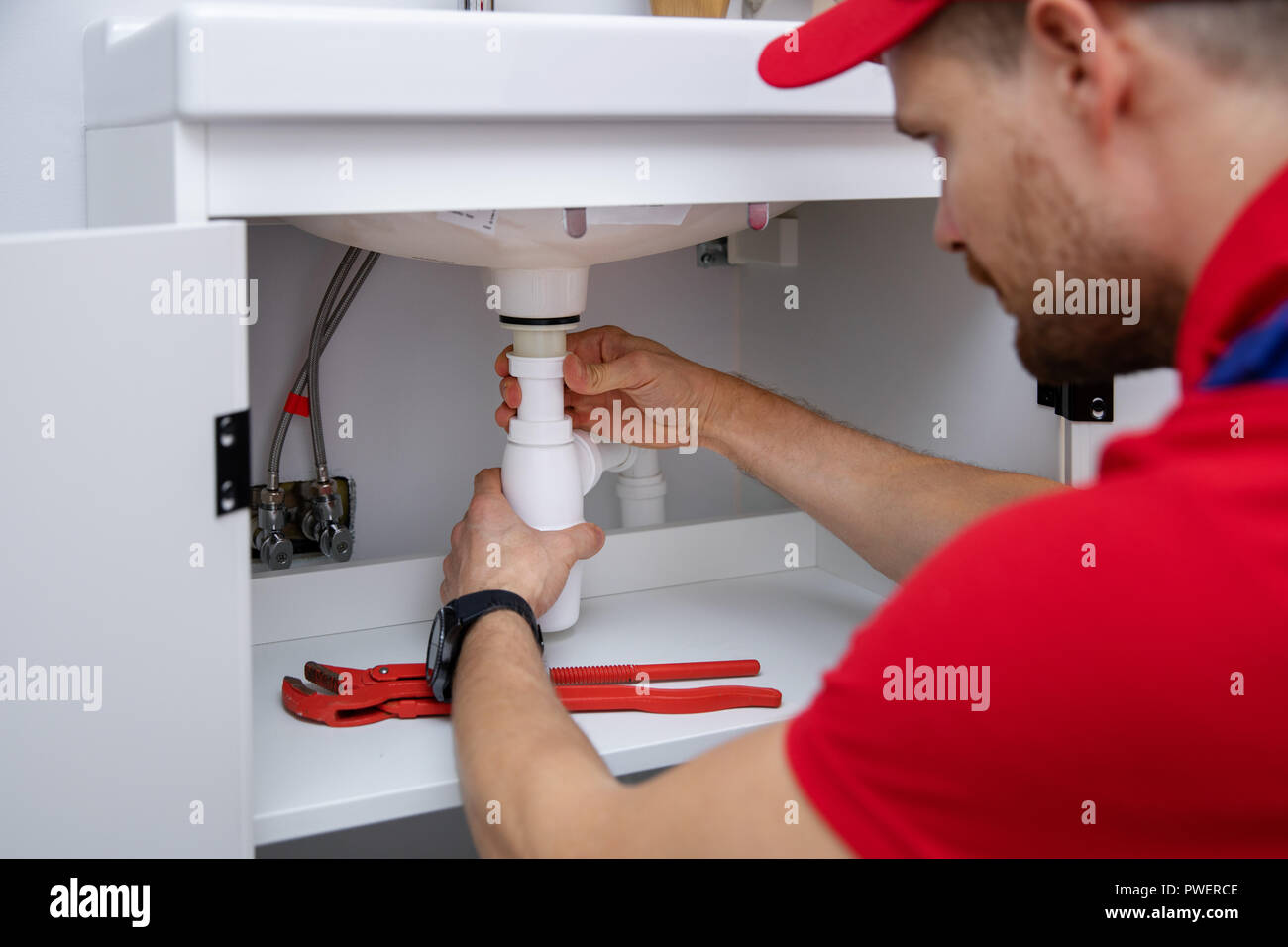 Plumber installazione Sifone lavello in bagno interno Foto Stock