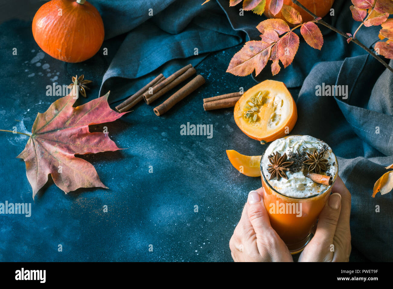 Succo di zucca con panna montata in mano femminile sul buio. Autunno autunno o inverno bevanda calda. Accogliente bevanda salutare. Foto Stock
