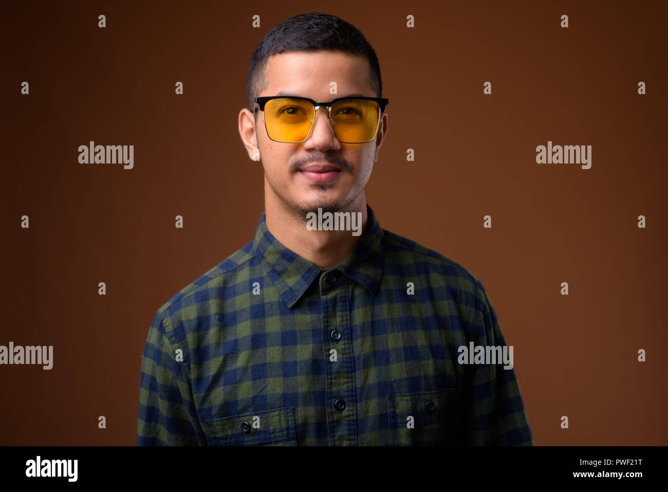 Giovani multi-etnico uomo asiatico contro sfondo marrone Foto Stock