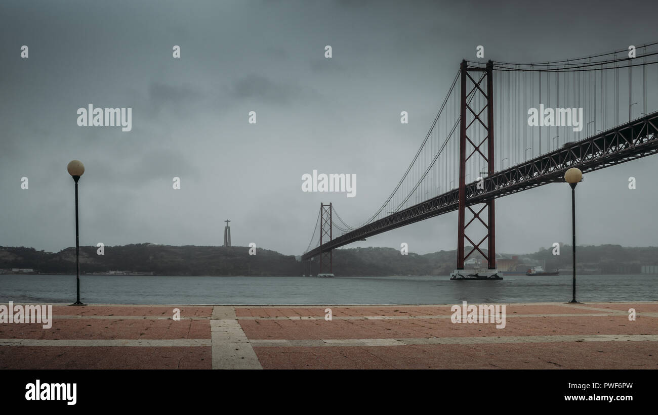 Cloudscape vista del 25 aprile il ponte sul fiume Tagus e Cristo re un monumento a Lisbona, Portogallo. Foto Stock
