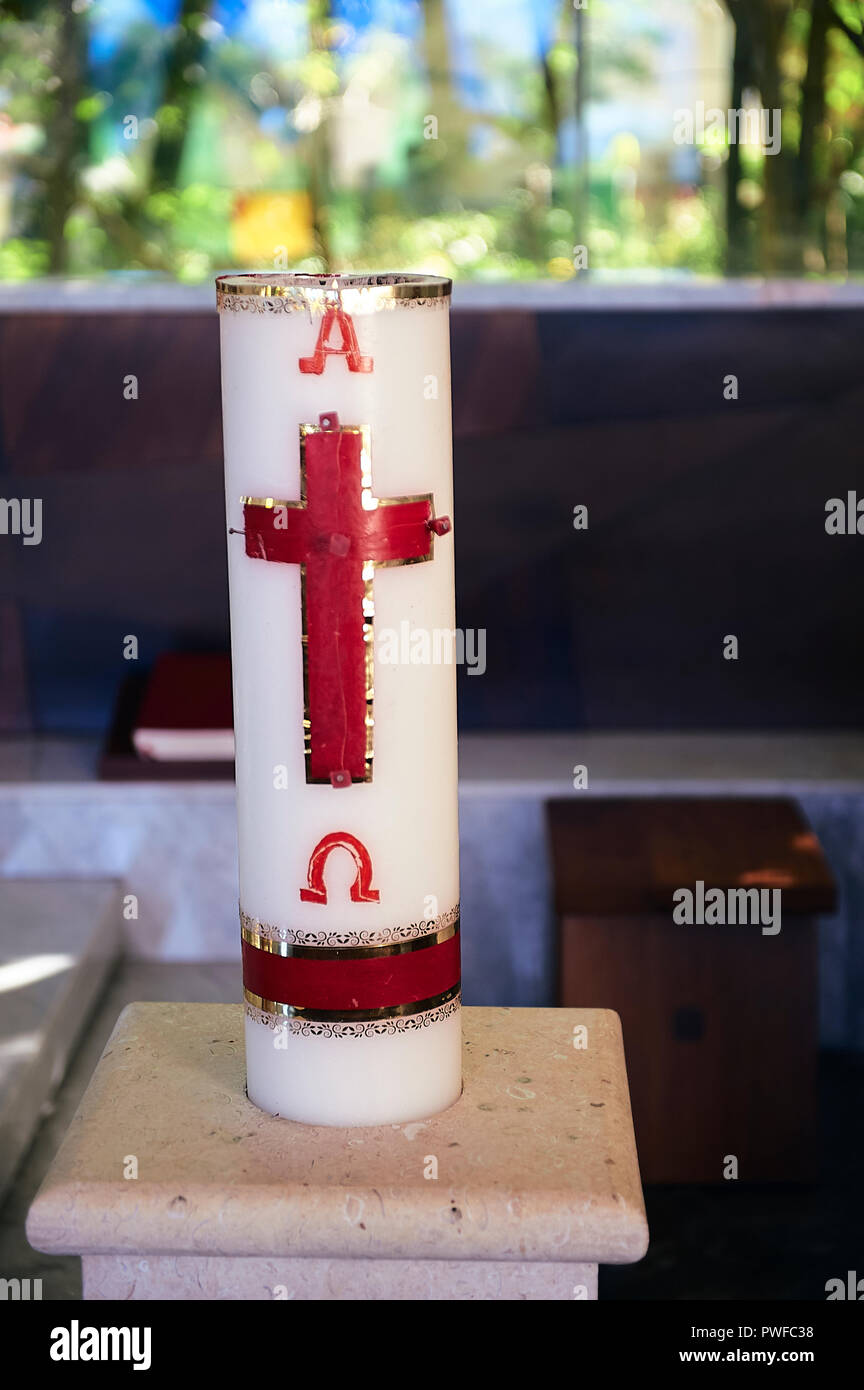 Cero pasquale alla chiesa cattolica, che mostra la croce in rosso e dorato, e le lettere Greche Alfa e Omega Foto Stock