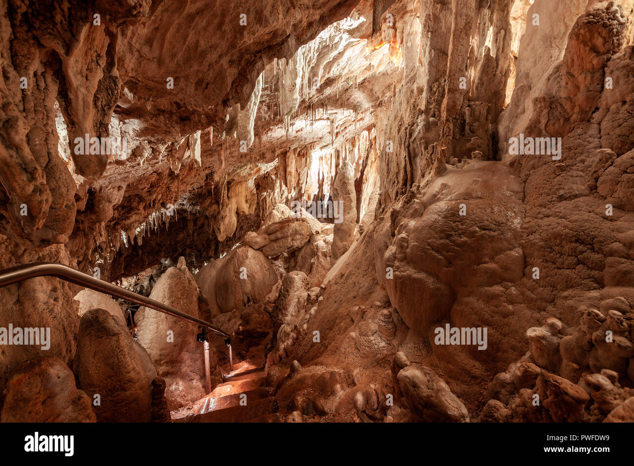 Scale che conducono verso il basso tra le stalattiti e le stalagmiti nella grotta di gloria. Kosciuszko National Park, Australia Foto Stock