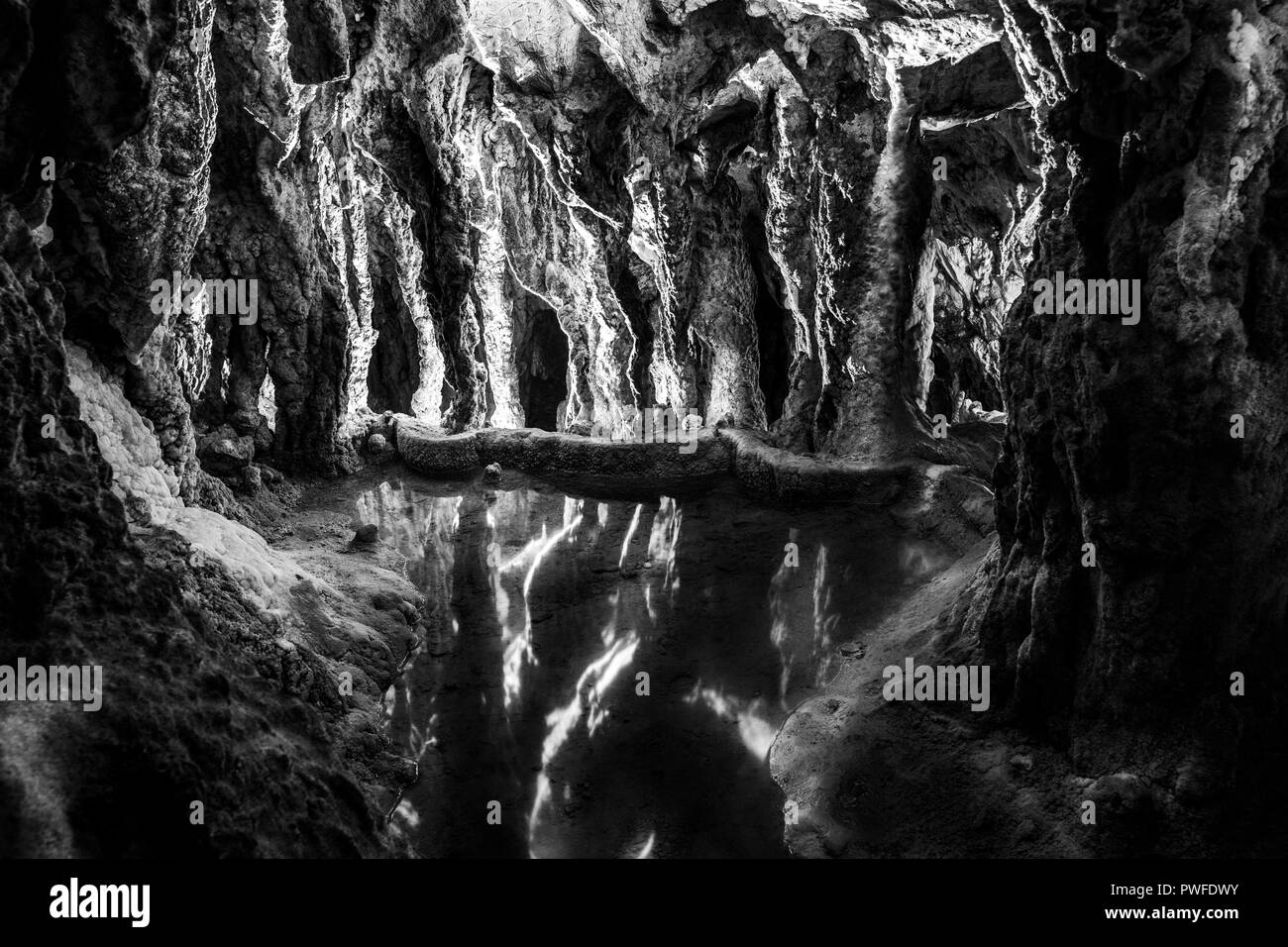 Le splendide formazioni rocciose nella grotta di pietra calcarea che riflette in acqua in bianco e nero Foto Stock