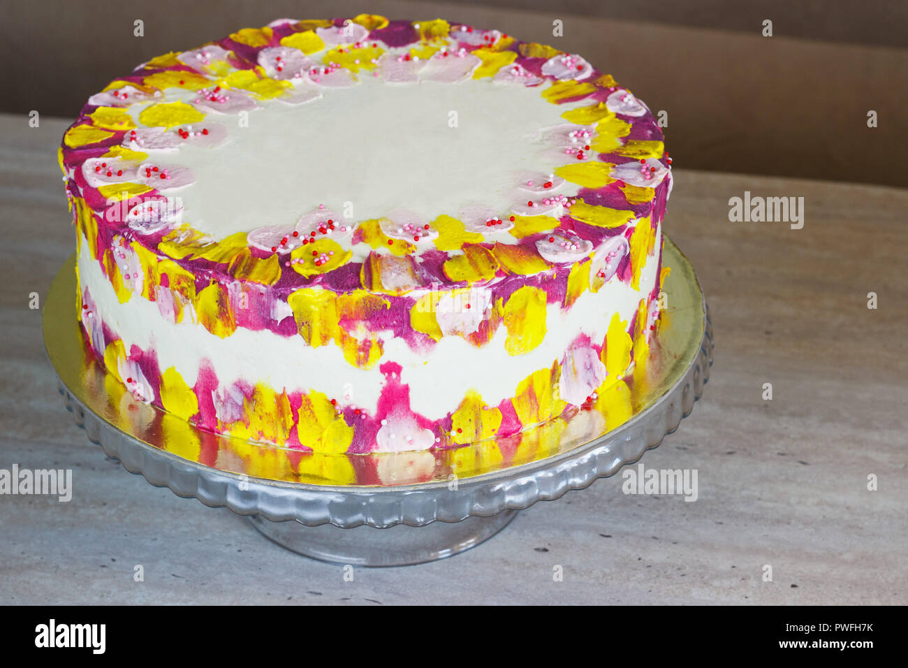 Bianco torta di compleanno con colorati spruzza su uno sfondo luminoso. Foto Stock