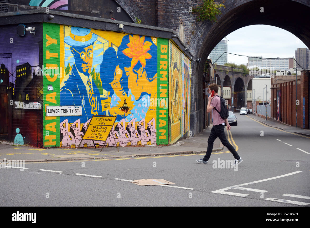 Giovane uomo cammina passato Arte di Strada nel vecchio Run-Down strade di Digbeth Birmingham Inghilterra Foto Stock