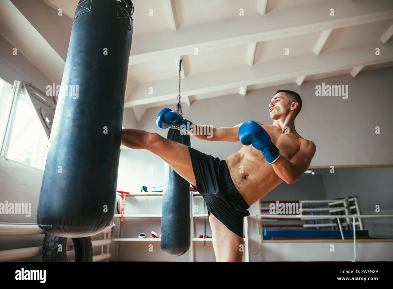 Boxer maschio allenamento calcio alto sul sacco da boxe in palestra. Sport  concept Foto stock - Alamy