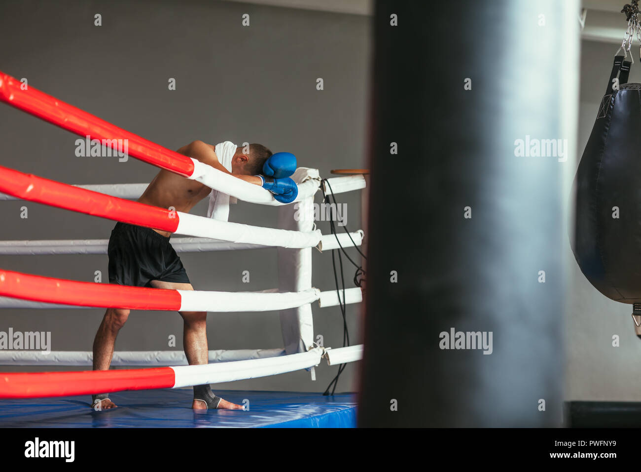 Stanco boxer in appoggio nel pugilato ring, testa su guanti. Break in battaglia Foto Stock