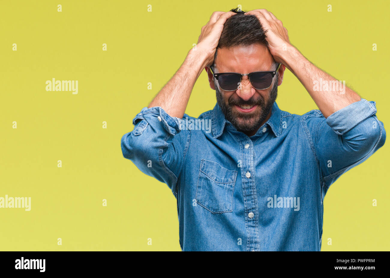 Adulto uomo ispanico indossando occhiali da sole su sfondo isolato che  soffrono di mal di testa disperato e ha sottolineato perché il dolore e  l'emicrania. Le mani sulla testa Foto stock -