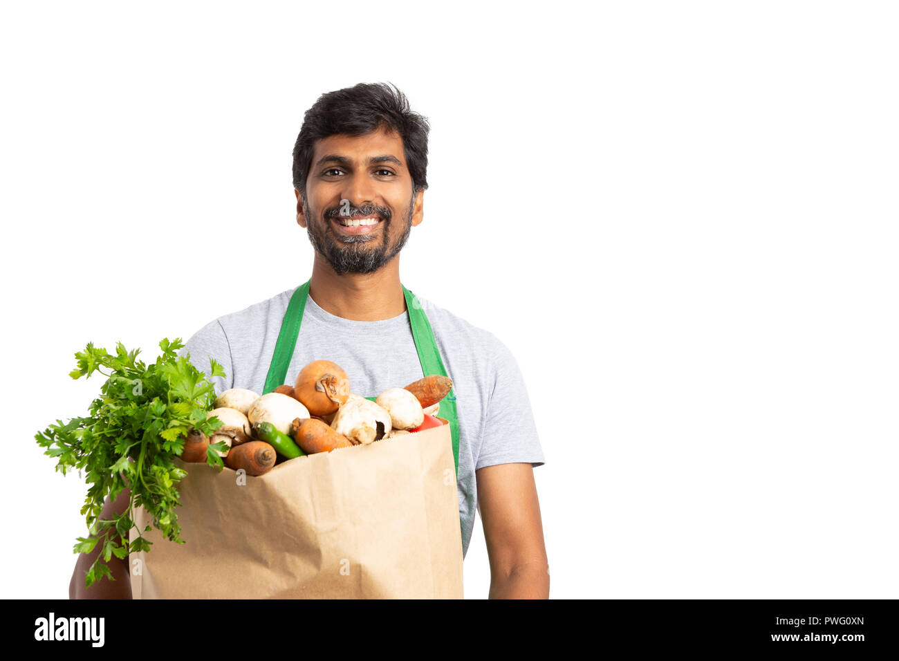 Gentile indian fruttivendolo dipendente azienda verdura fresca borsa come un sano concetto con sorriso isolato su bianco Foto Stock