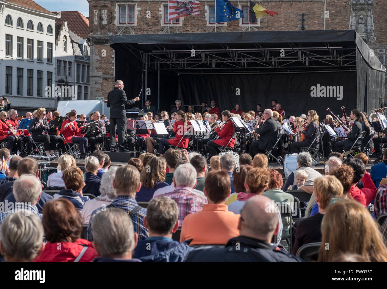 Un pubblico che godono di un open air concerto di musica durante una soleggiata giornata di settembre nella piazza del mercato, Markt, Bruges, Fiandre, in Belgio. Foto Stock