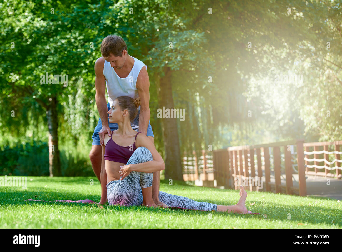A piena lunghezza shot della giovane donna a praticare yoga con il suo maschio istruttore. Foto Stock