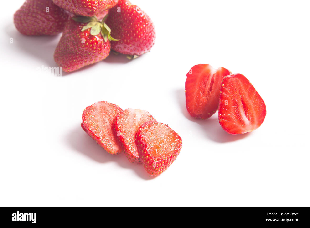 Dolce con fragole a fette, semi e frutti di bosco interi. Crudo fresco di bacche rosse isolato su sfondo bianco. Foto Stock